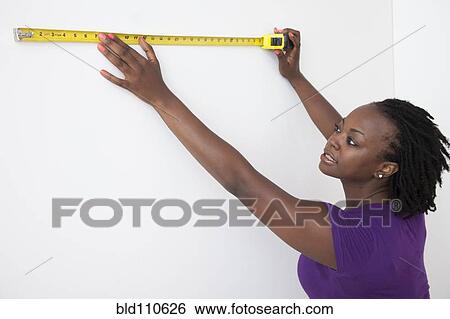 Black woman measuring wall View Large Photo Image Stock Photograph - Black woman measuring wall. Fotosearch