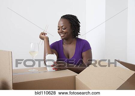 Stock Photo - Black woman unpacking and eating Asian food. Fotosearch