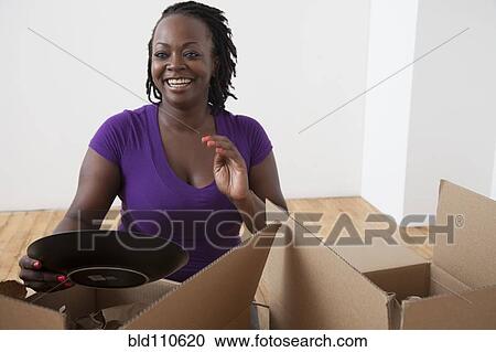 Stock Image - Black woman unpacking boxes. Fotosearch