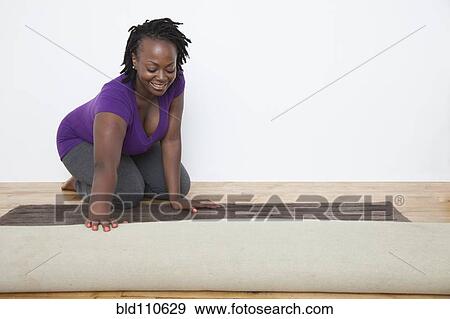 Black woman unrolling carpet View Large Photo Image Stock Photo - Black woman unrolling carpet. Fotosearch