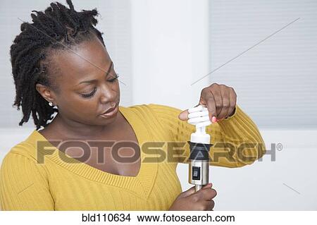 Picture - Black woman using CFL light bulb. Fotosearch