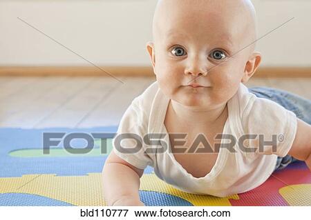 Stock Photo - Caucasian baby crawling on plastic mat. Fotosearch