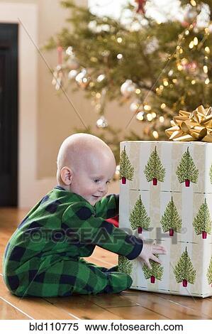 Stock Photography - Caucasian baby playing with Christmas present. Fotosearch