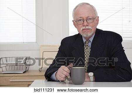 Stock Image - Caucasian businessman drinking coffee in office. Fotosearch