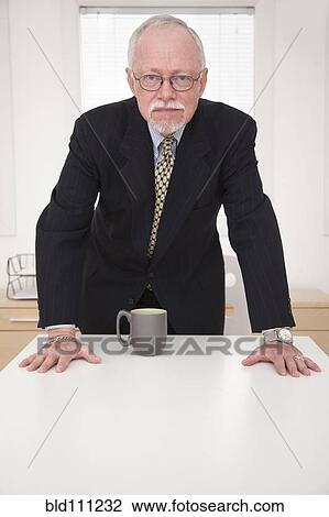Stock Image - Caucasian businessman leaning over table. Fotosearch