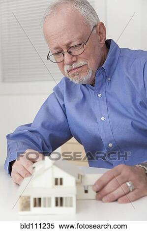 Stock Photography - Caucasian businessman working on model of house. Fotosearch