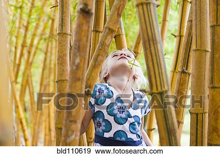 Stock Photo - Caucasian girl looking at bamboo stalks. Fotosearch