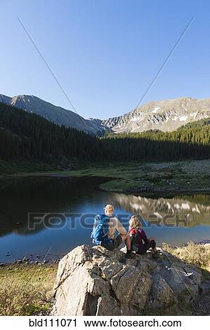 Stock Image - Caucasian hikers sitting on boulder. Fotosearch