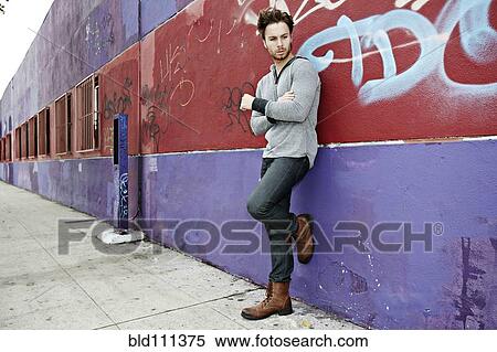 Stock Photography - Caucasian man leaning against graffiti wall. Fotosearch
