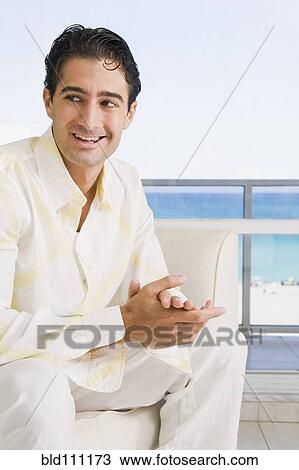 Stock Image - Caucasian man sitting in armchair. Fotosearch