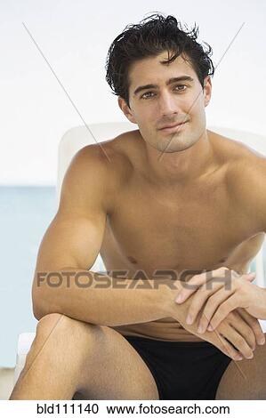 Stock Image - Caucasian man sitting outdoors. Fotosearch