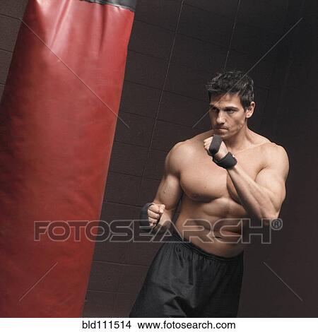 Picture - Caucasian man using punching bag. Fotosearch