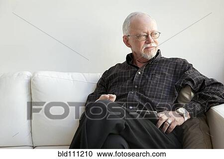 Stock Image - Caucasian man using tablet computer on sofa. Fotosearch