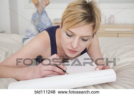 Stock Photo - Caucasian woman making notes on bed. Fotosearch