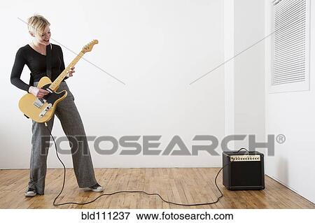 Stock Photo - Caucasian woman playing electric guitar. Fotosearch