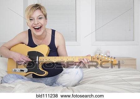Stock Photo - Caucasian woman playing electric guitar. Fotosearch