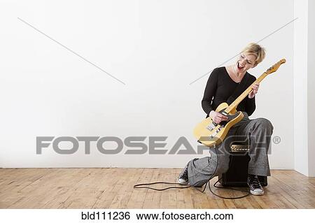 Stock Photograph - Caucasian woman playing electric guitar. Fotosearch