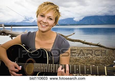 Caucasian woman playing guitar near lake View Large Photo Image Stock Image - Caucasian woman playing guitar near lake. Fotosearch