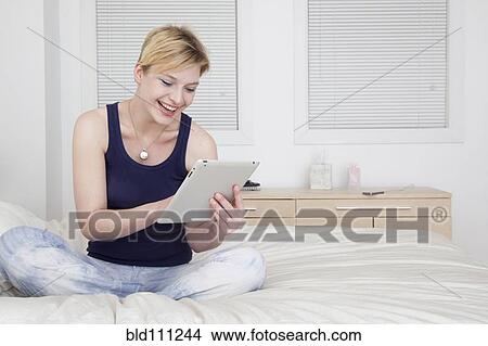 Caucasian woman using tablet computer on bed View Large Photo Image Picture - Caucasian woman using tablet computer on bed. Fotosearch