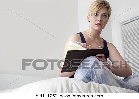 Caucasian woman writing in diary on bed View Large Photo Image Stock Image - Caucasian woman writing in diary on bed. Fotosearch