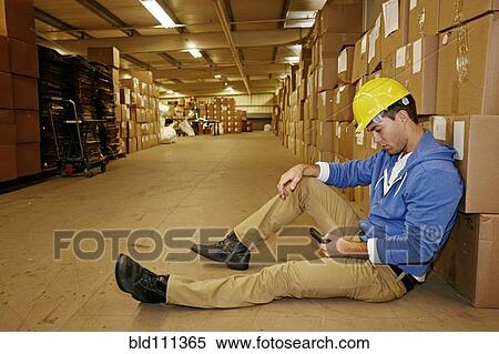 Caucasian worker using cell phone in warehouse View Large Photo Image Stock Photography - Caucasian worker using cell phone in warehouse. Fotosearch