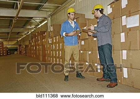Stock Photo - Caucasian workers talking in warehouse. Fotosearch