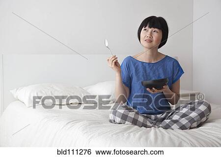 Chinese woman eating on bed View Large Photo Image Stock Photograph - Chinese woman eating on bed. Fotosearch