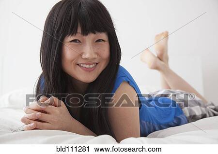 Stock Image - Chinese woman laying on bed. Fotosearch