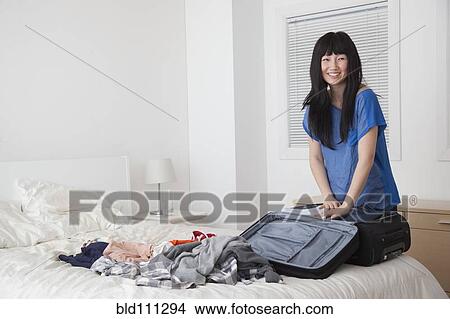 Chinese woman packing suitcase in bedroom View Large Photo Image Picture - Chinese woman packing suitcase in bedroom. Fotosearch
