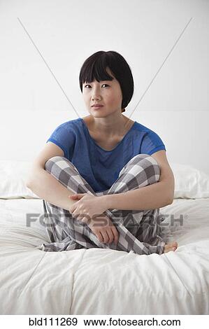 Stock Photo - Chinese woman sitting on bed. Fotosearch