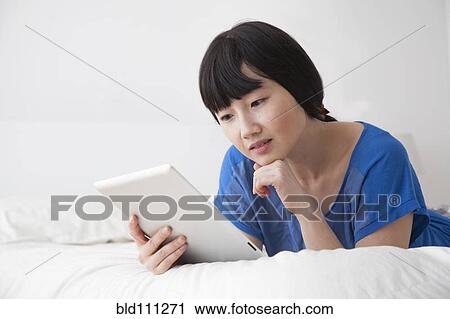 Chinese woman using tablet computer on bed View Large Photo Image Stock Image - Chinese woman using tablet computer on bed. Fotosearch