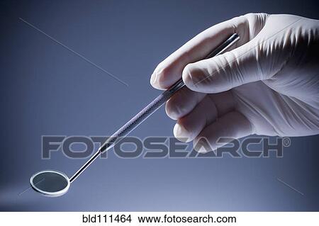 Picture - Close up of Hispanic dentist holding mirror. Fotosearch