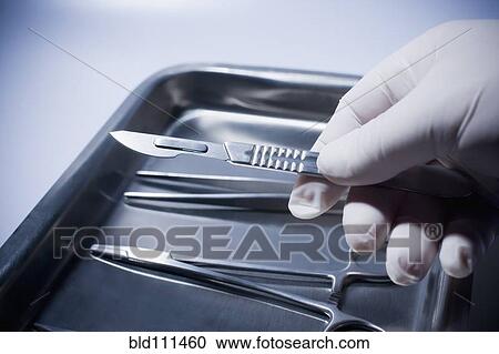 Stock Image - Close up of Hispanic doctor holding surgical equipment. Fotosearch