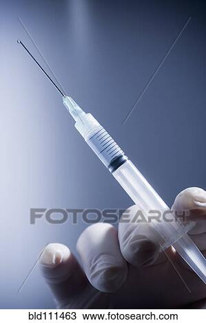 Stock Image - Close up of Hispanic doctor holding syringe. Fotosearch