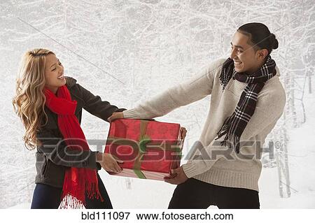 Stock Photo - Couple fighting over present in snow. Fotosearch