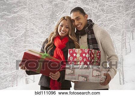Stock Photograph - Couple holding presents in snow. Fotosearch