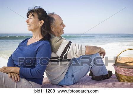 Stock Photo - Couple relaxing at picnic on beach. Fotosearch