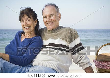 Stock Photo - Couple relaxing at picnic on beach. Fotosearch
