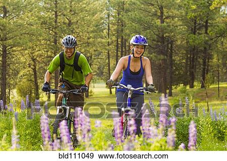 Couple riding mountain bikes in meadow View Large Photo Image Stock Photo - Couple riding mountain bikes in meadow. Fotosearch