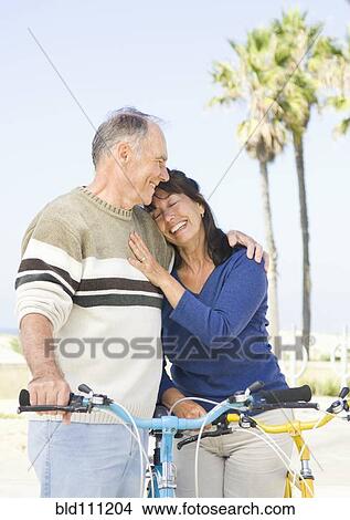 Picture - Couple walking bicycles on beach. Fotosearch