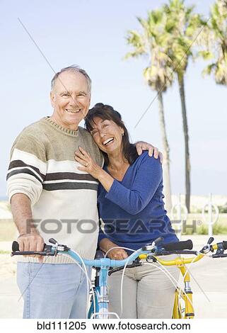 Stock Photography - Couple walking bicycles on beach. Fotosearch