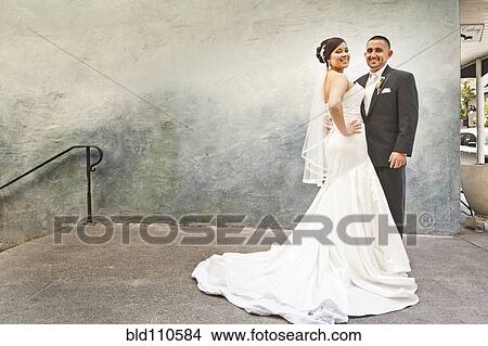 Picture - Hispanic bride and groom hugging. Fotosearch