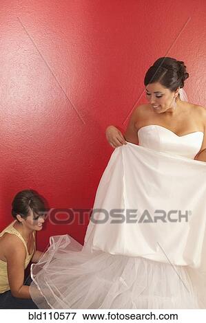 Stock Photo - Hispanic bride putting on wedding dress. Fotosearch
