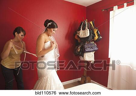 Stock Photograph - Hispanic bride putting on wedding dress. Fotosearch
