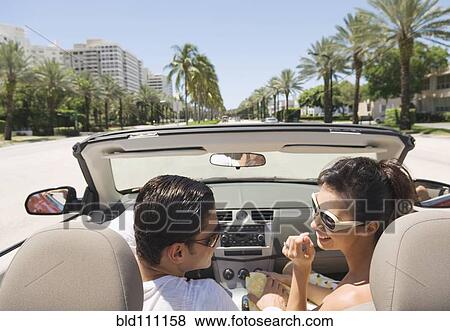 Stock Photo - Hispanic couple driving in convertible. Fotosearch