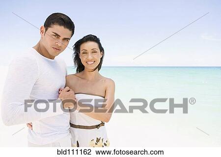 Stock Image - Hispanic couple holding hands on beach. Fotosearch