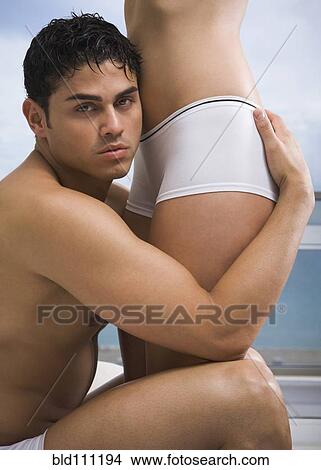 Picture - Hispanic couple hugging in bedroom. Fotosearch