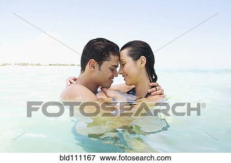 Stock Photo - Hispanic couple hugging in water. Fotosearch