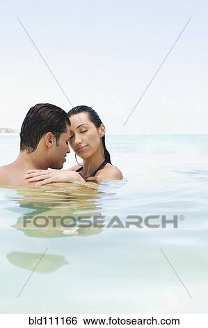 Hispanic couple hugging in water View Large Photo Image Stock Photograph - Hispanic couple hugging in water. Fotosearch