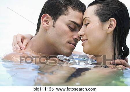 Stock Photography - Hispanic couple hugging in water. Fotosearch